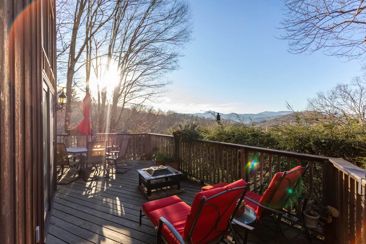 A wrap-around deck with comfortable outdoor seating and an inviting fire pit, all oriented to capture the sweeping sunset view of the mountains. The deck is set up for both relaxation and socializing, seamlessly extending the gathering space into the outdoors.