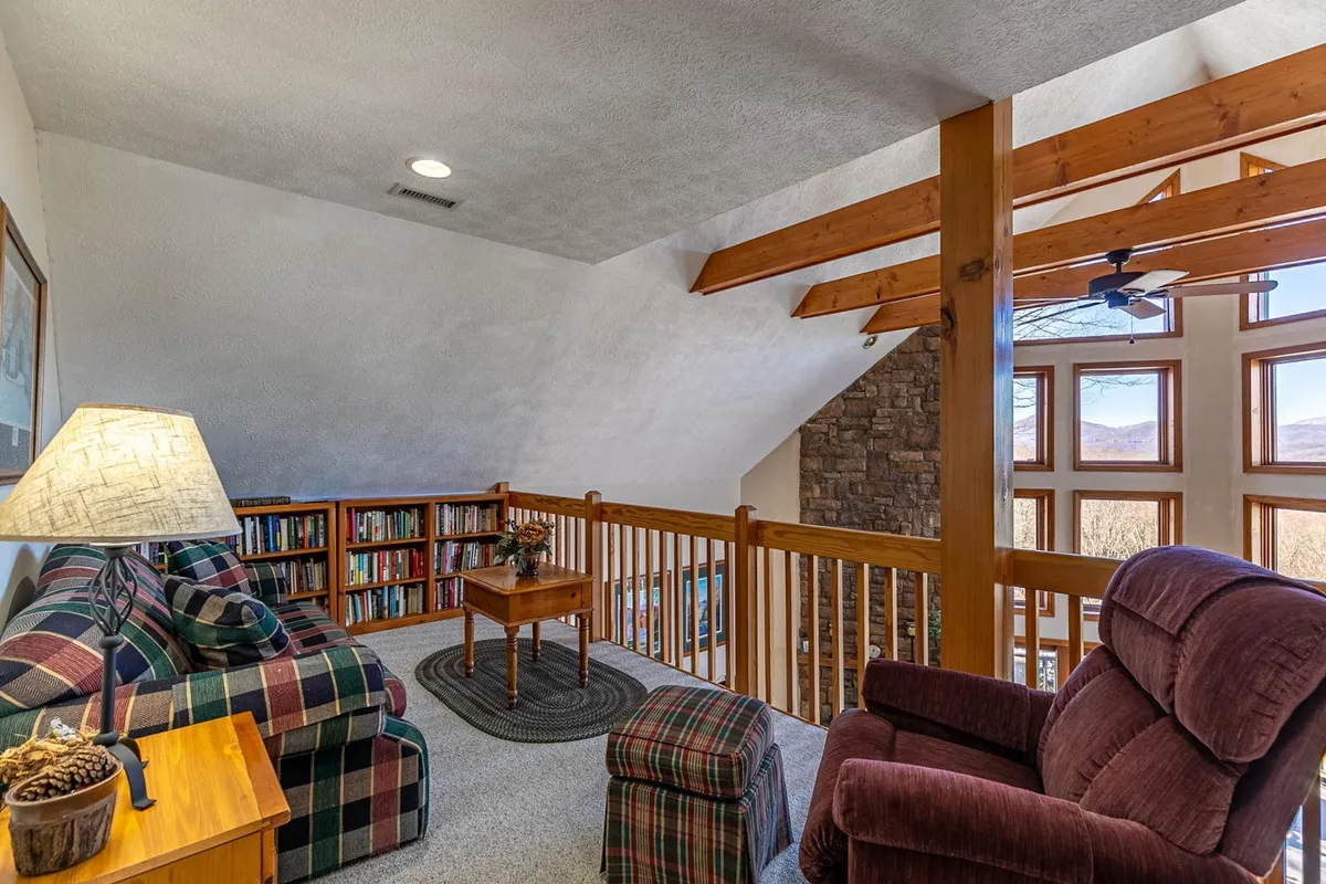 A bright sitting area with plaid sofas, large windows framing mountain views, and bookshelves. The inviting space encourages socializing, reading, and appreciating the scenery beyond the glass, making it a hub for relaxation in any season.